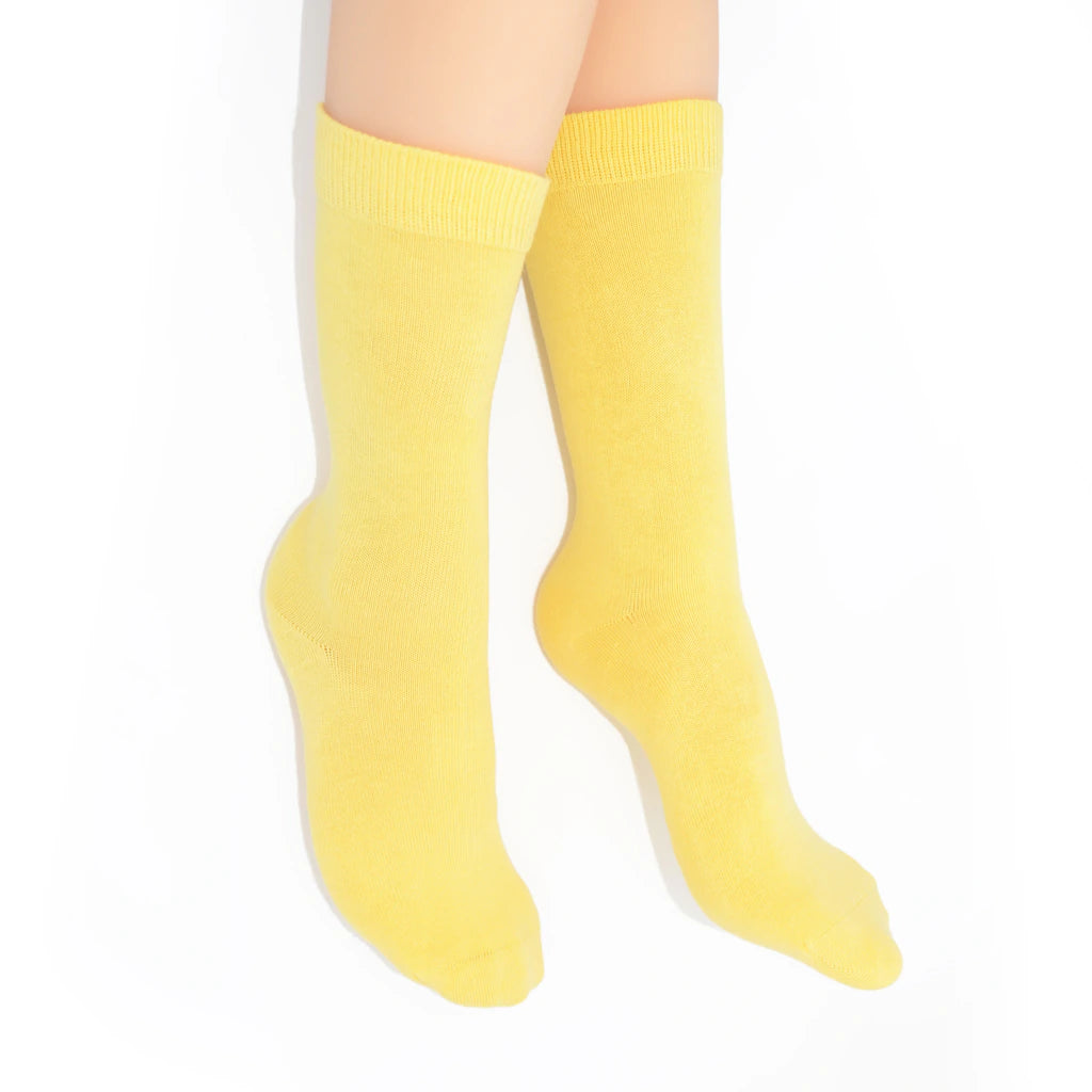 Legs modelling yellow socks on a white background