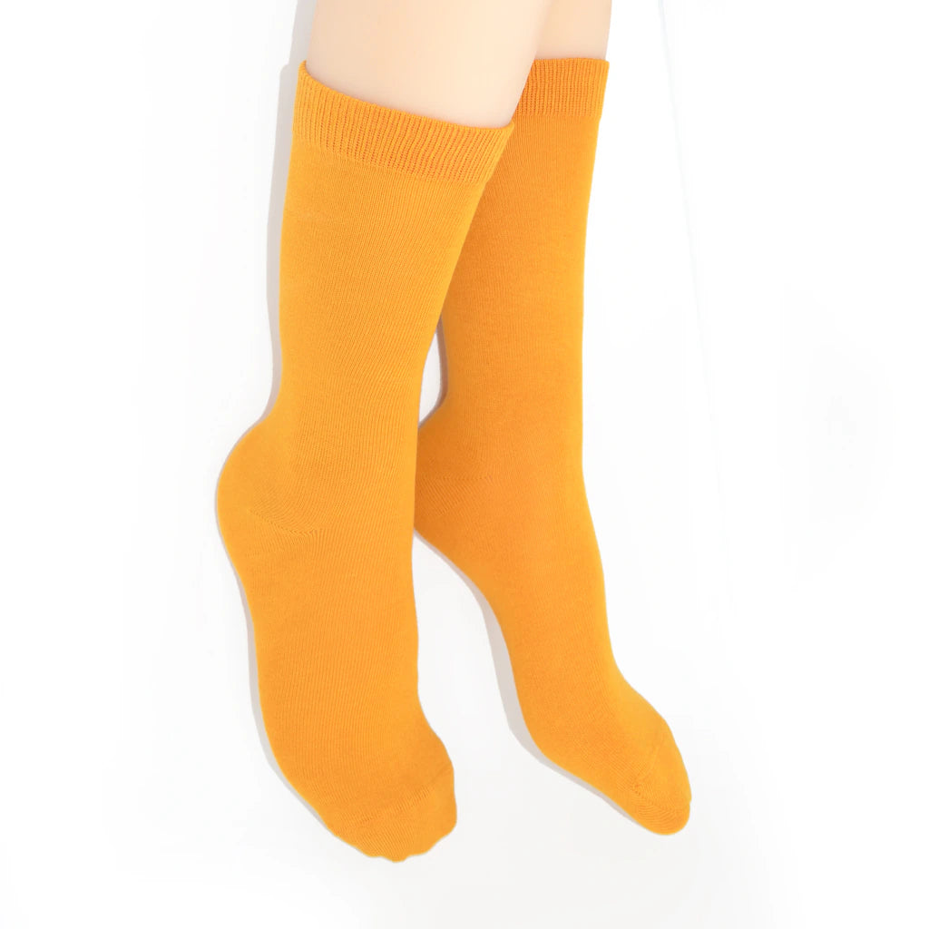 Legs modelling orange socks on a white background