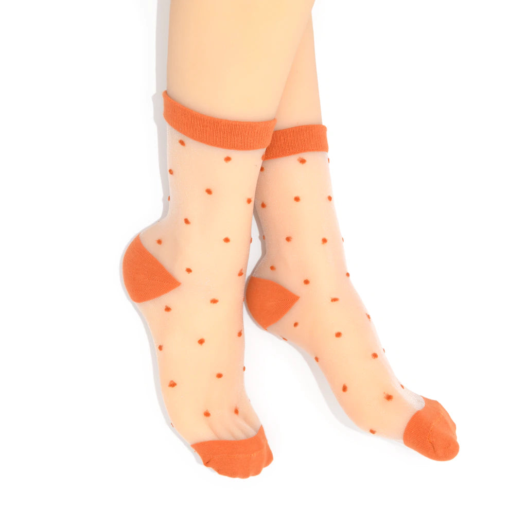 Sheer socks with orange polka dots and cuffs on a white background