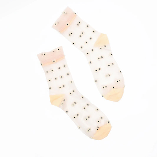 A pair of sheer white ankle socks with small black polka dots and soft peach-colored toe and cuff accents, displayed on a clean white background.