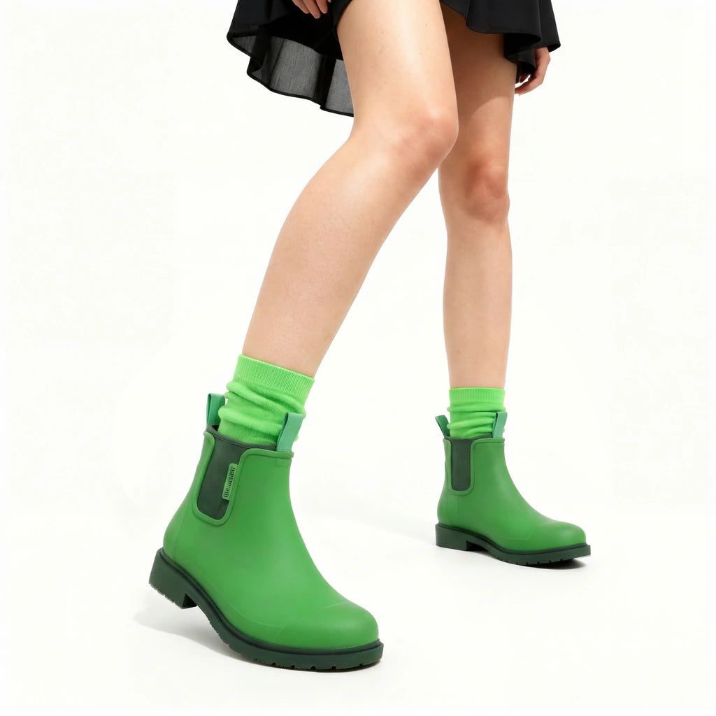 Green rain boots worn with bright green socks on a white background
