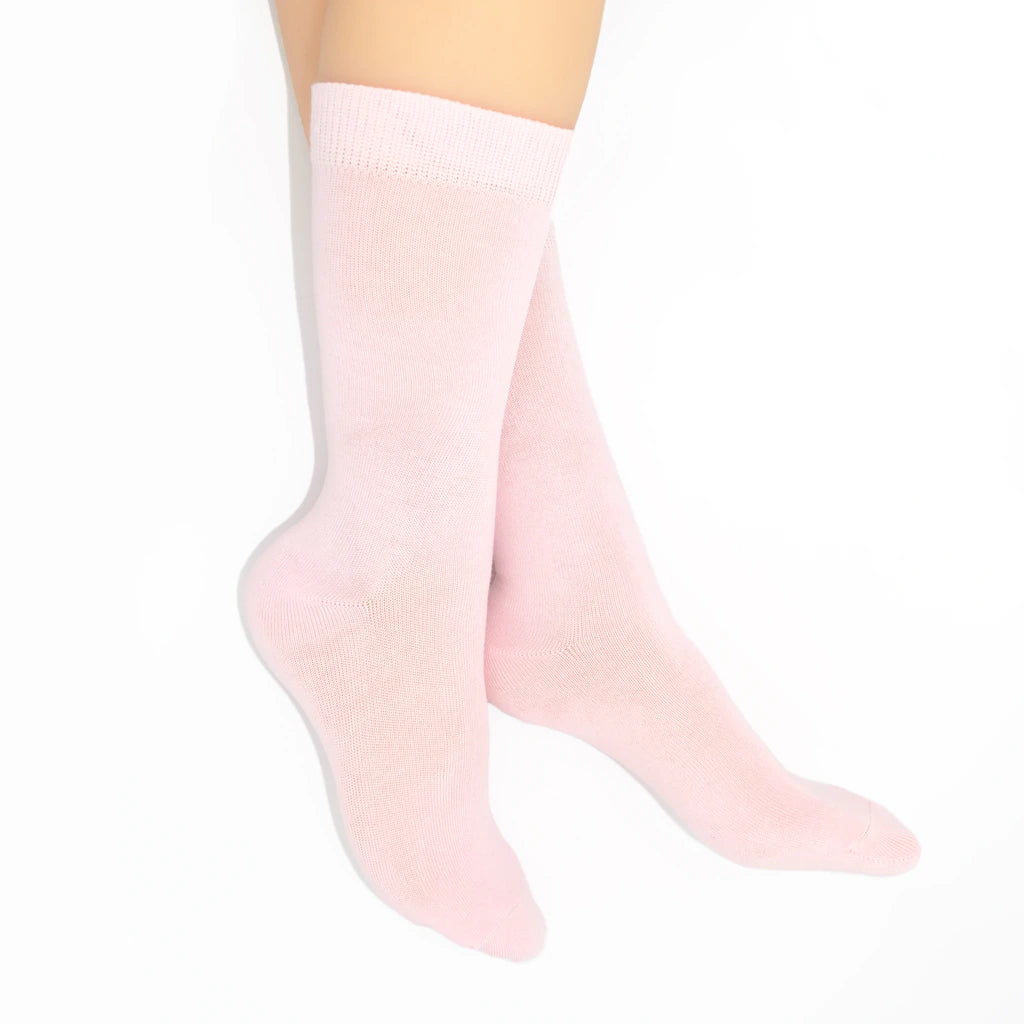 Legs modelling light pink socks on a white background