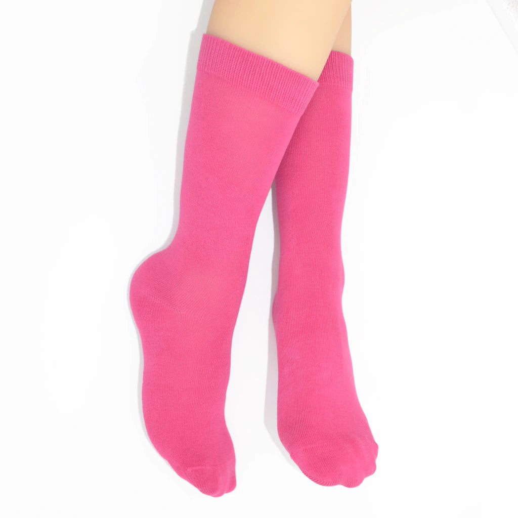 Legs modelling bright pink socks on a white background