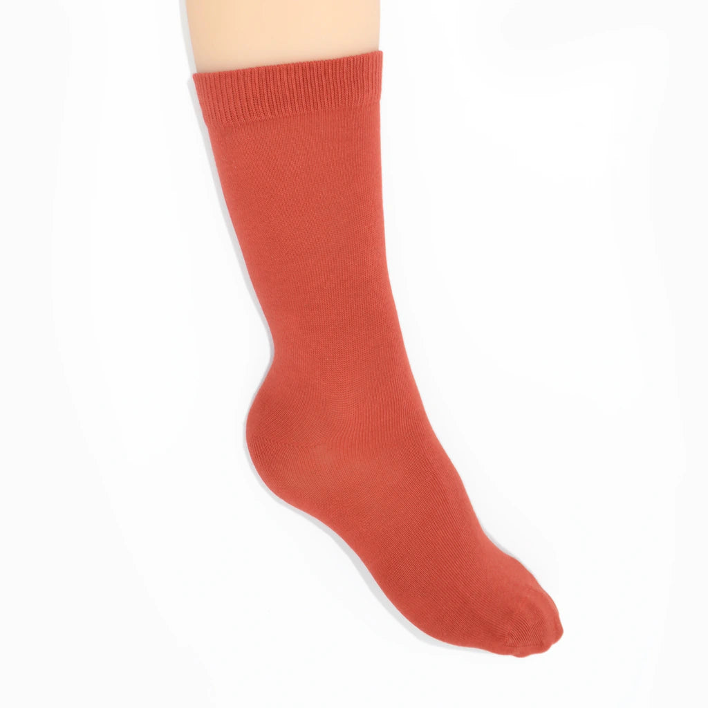 Leg modelling rust coloured socks on a white background