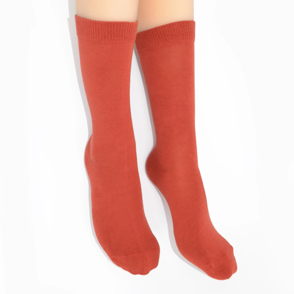 Legs modelling rust coloured socks on a white background