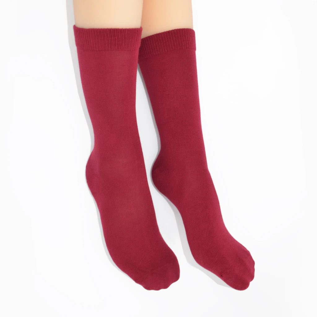 Legs modelling berry red socks on a white background