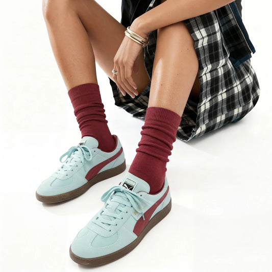 Person wearing maroon socks with white sneakers on a white background