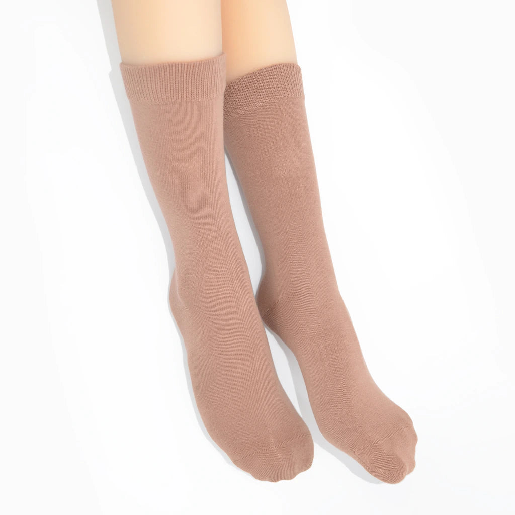 Legs modelling beige socks on a white background
