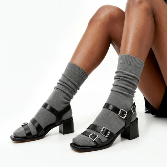 Gray socks with black buckled sandals on a white background