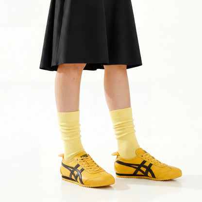 Person wearing a yellow skirt, socks, and sneakers on a white background
