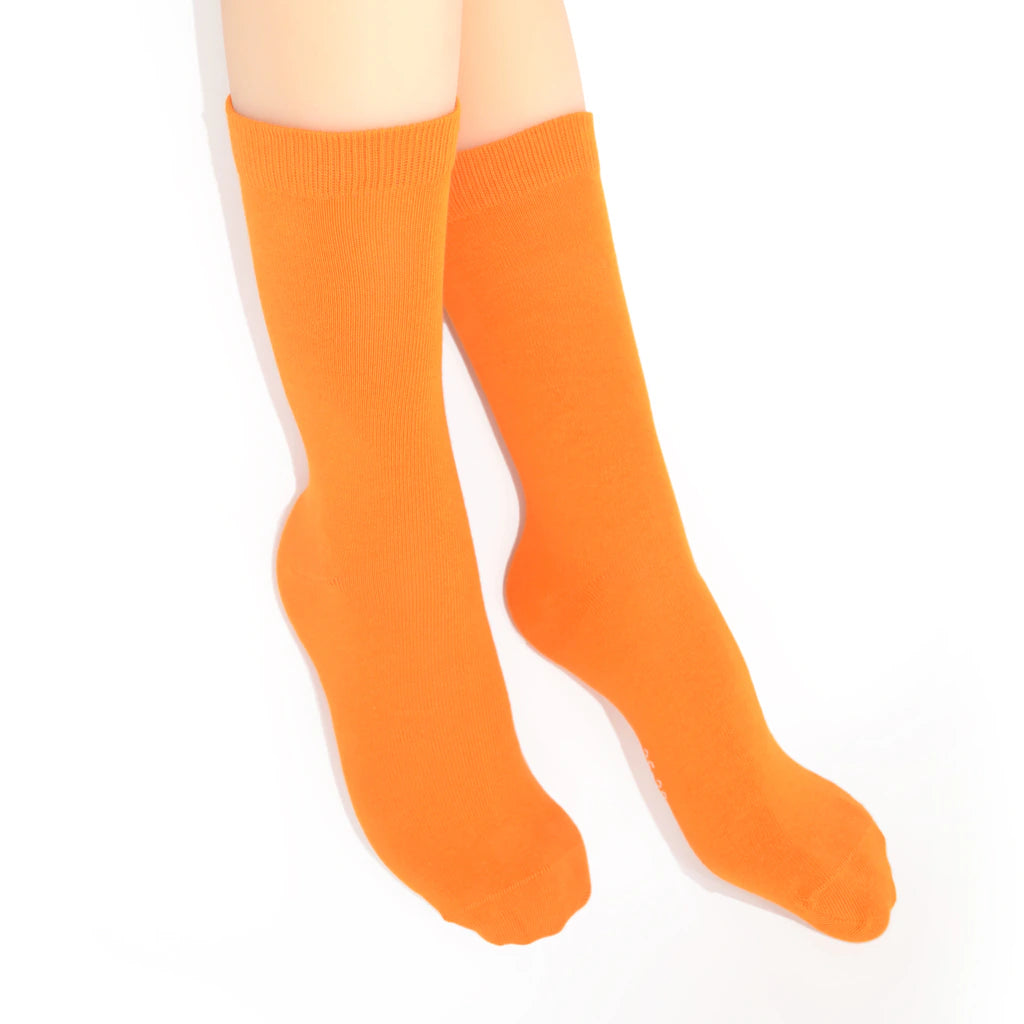 Legs modelling orange socks on a white background