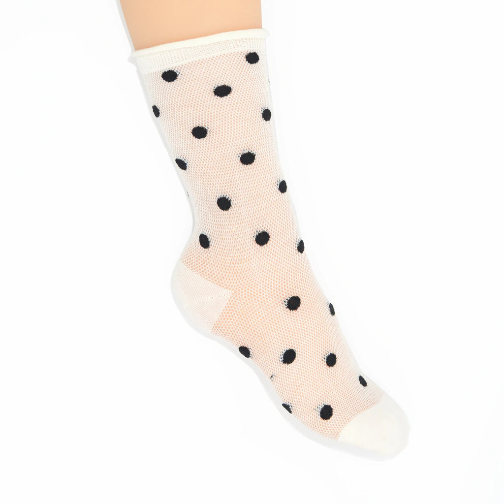 A single sheer ankle sock with black polka dots, worn on a foot against a plain white background.