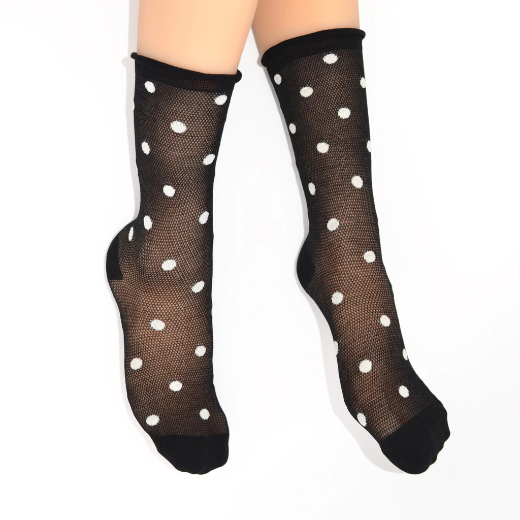Black sheer mesh crew socks with white polka dots, shown on a model's feet against a plain white background.
