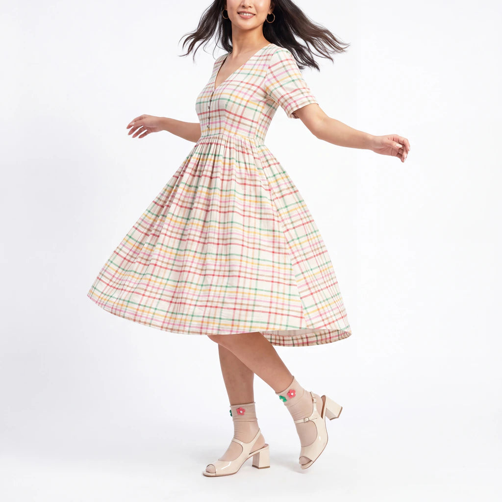 Woman wearing a pastel plaid dress on a white background
