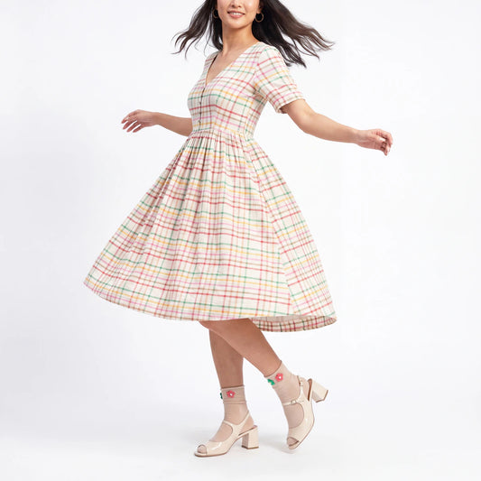 Woman wearing a pastel plaid dress on a white background