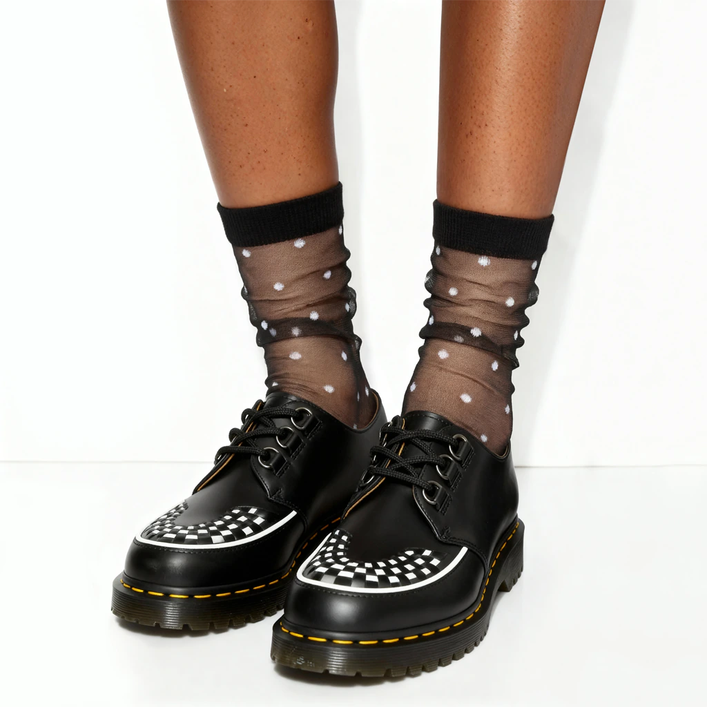 Black shoes with white polka dot trim worn with sheer black socks featuring white polka dots on a white background.