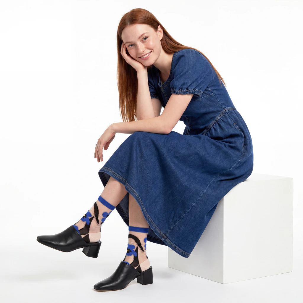 Woman wearing a blue dress and black shoes with blue accents on a white background