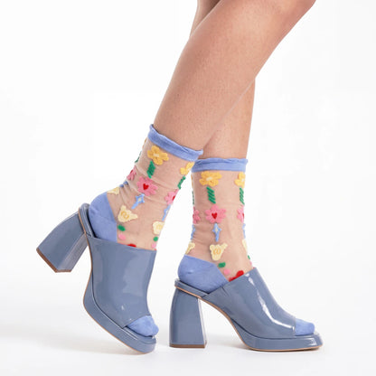 Blue shoes with floral sheer socks on a white background