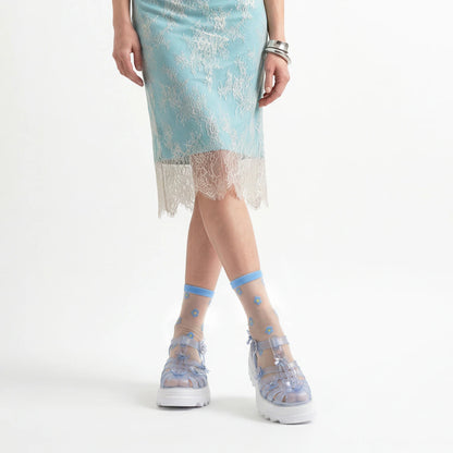 Person wearing a light blue lace dress with sheer socks and shoes on a white background