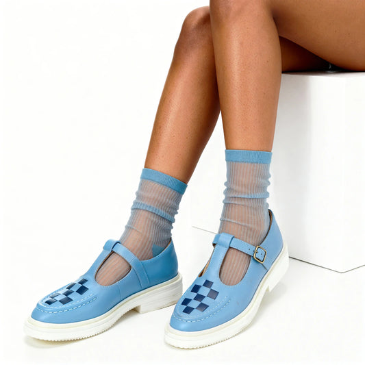 Blue shoes with checkered sole worn with sheer socks on a white background