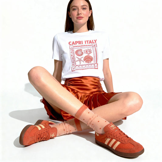 Woman wearing a white 'Capri Italy' t-shirt, orange skirt, and red sneakers on a white background