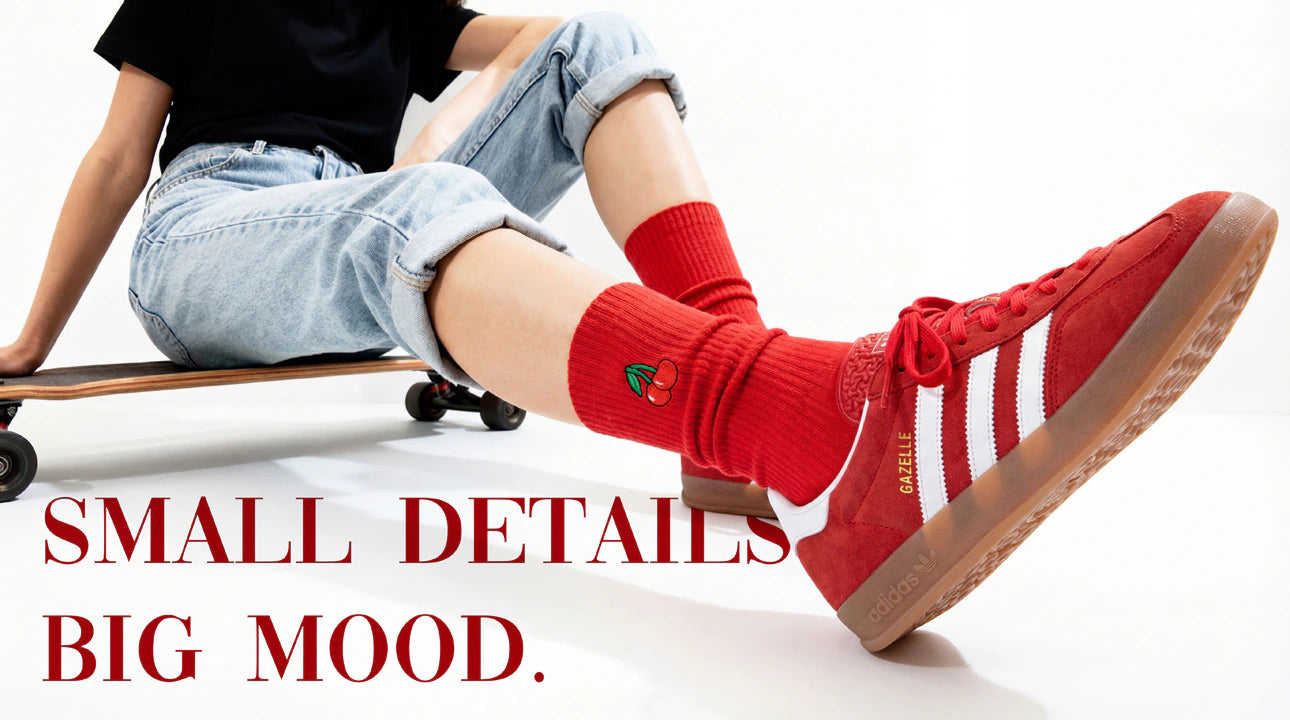Person wearing red Adidas shoes with a skateboard, sitting on a white background.