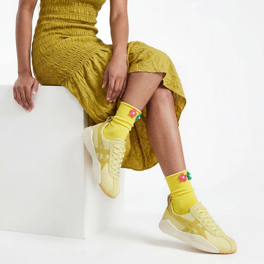Person wearing a yellow outfit with matching shoes and socks on a white background