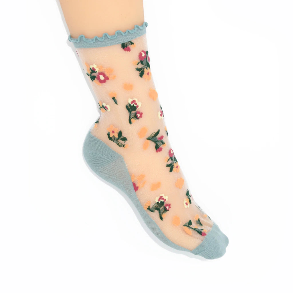 Sheer socks with floral pattern and light blue ruffled top on a white background