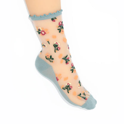 Sheer socks with floral pattern and light blue ruffled top on a white background