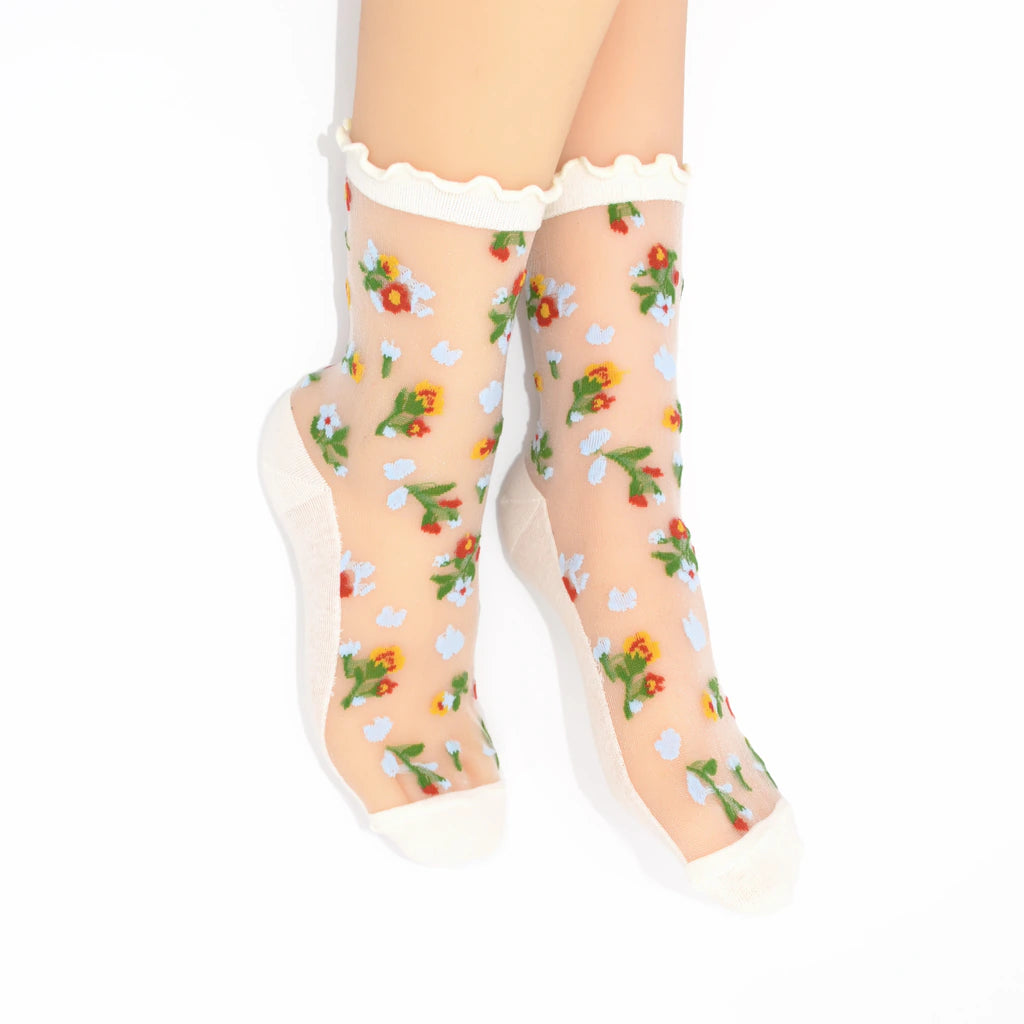 Sheer socks with floral pattern and white ruffled top on a white background