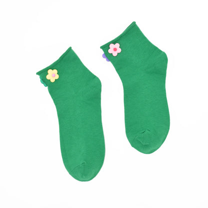 Pair of green socks with flower decorations on a white background