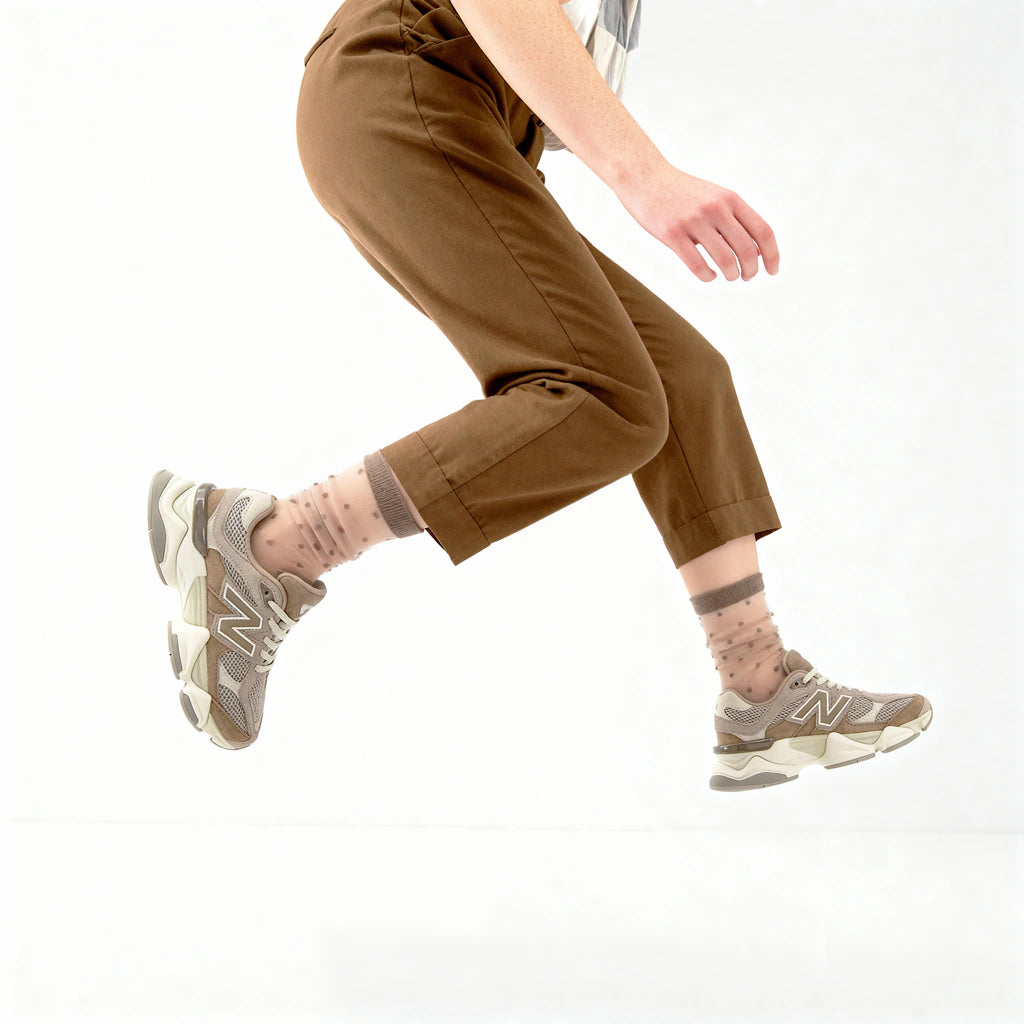 Person wearing brown pants and gray sneakers on a white background