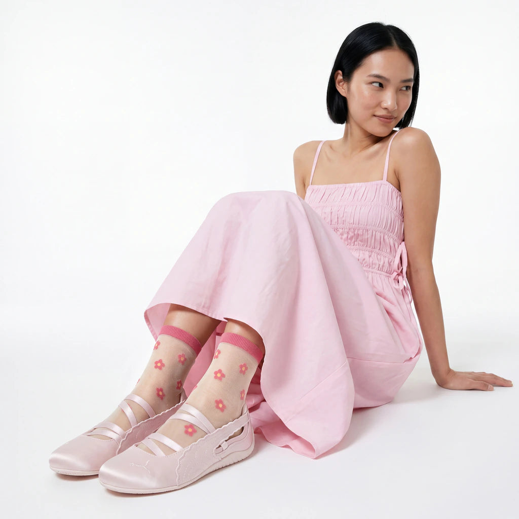 Woman wearing a pink dress and matching shoes with floral socks on a white background