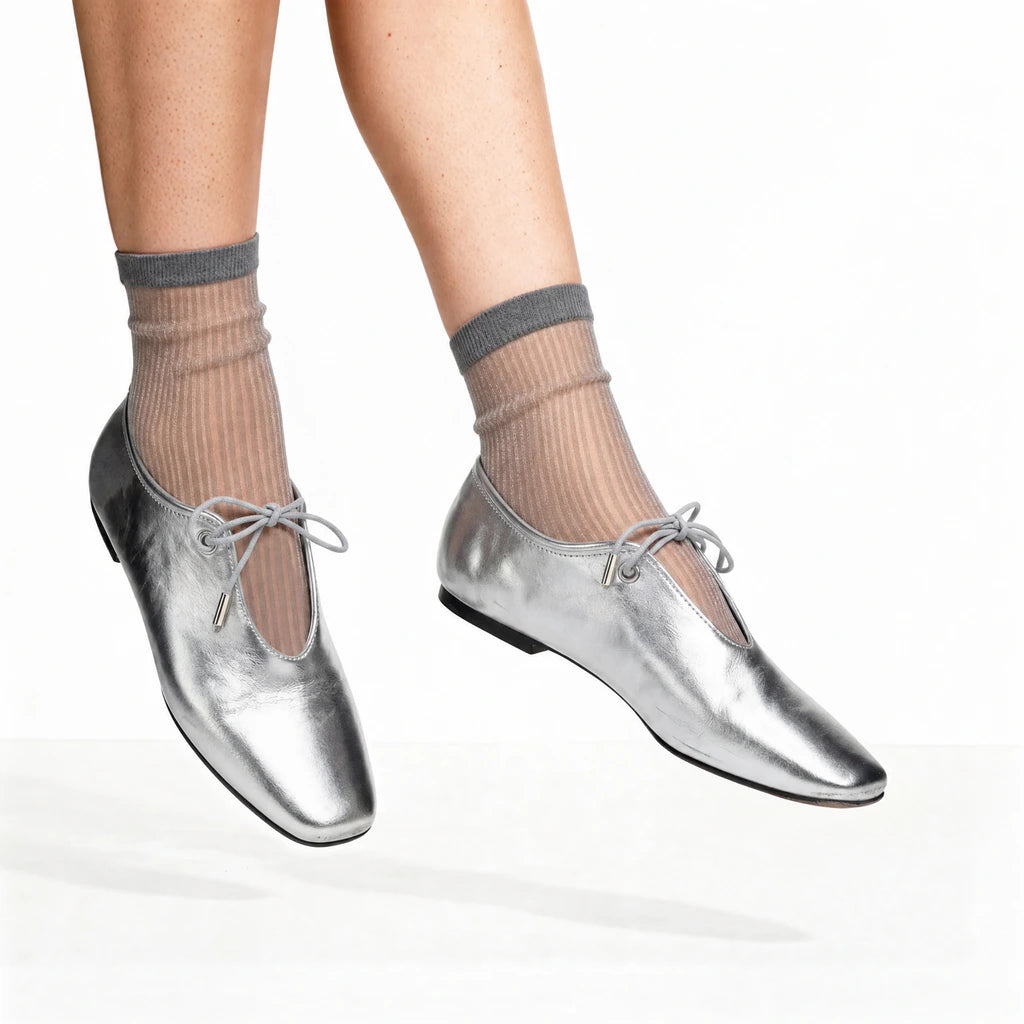 Silver shoes worn with grey socks on a white background