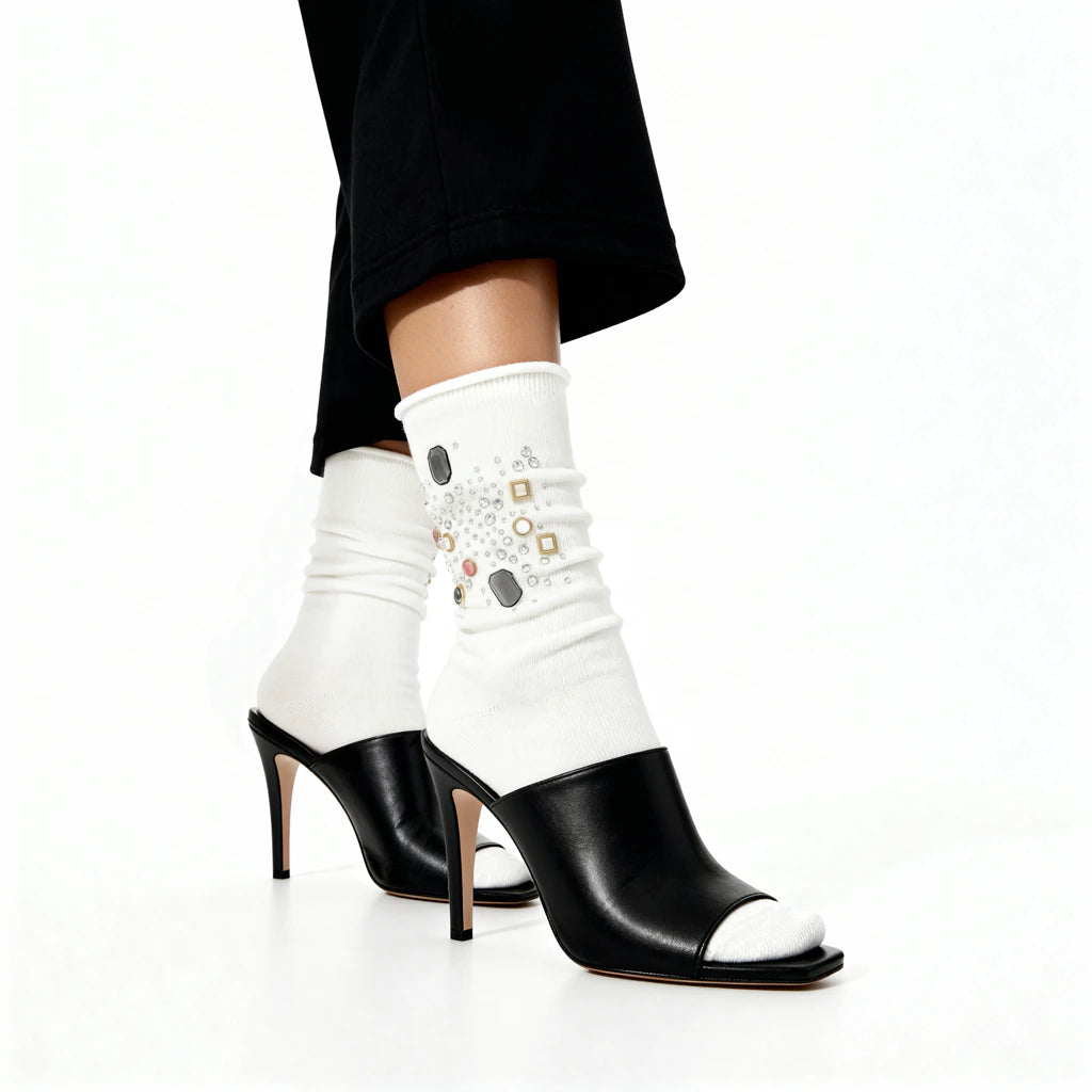 Black high-heeled shoes with white socks featuring decorative elements on a white background