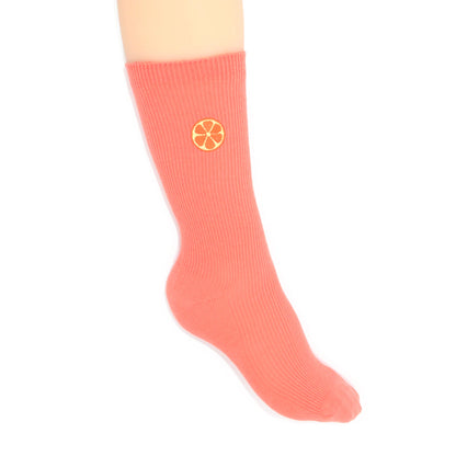 Coral sock with an embroidered grapefruit motif on a white background