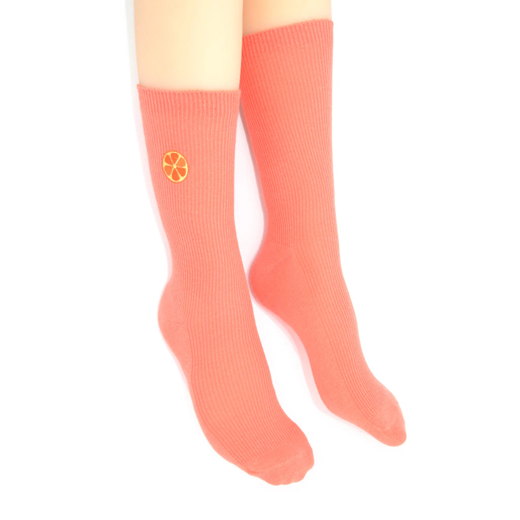 Coral sock with an embroidered grapefruit motif on a white background