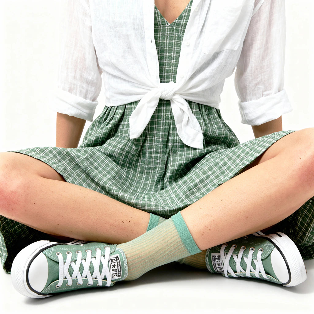 Person wearing green checkered dress, white shirt, and green sneakers with beige socks.