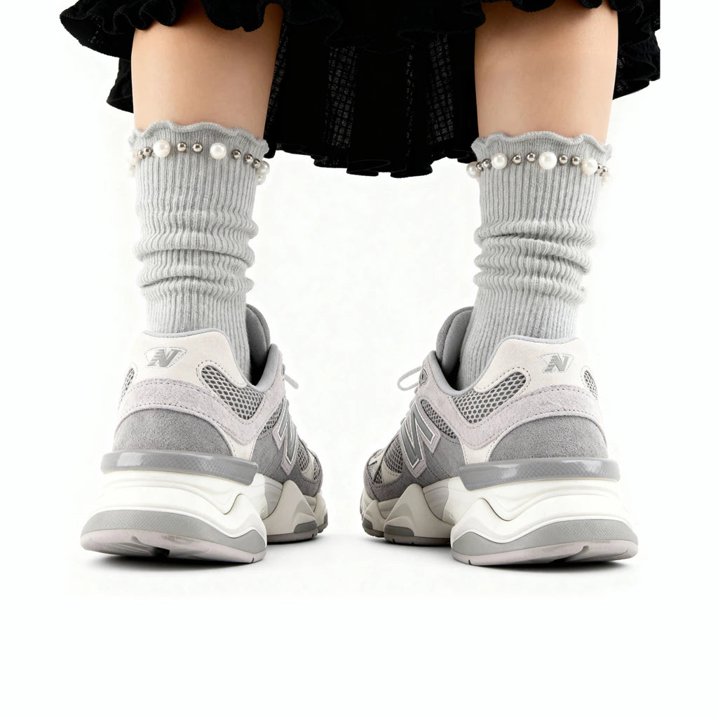 Gray sneakers with white soles worn by a person on a white background