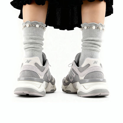 Gray sneakers with white soles worn by a person on a white background