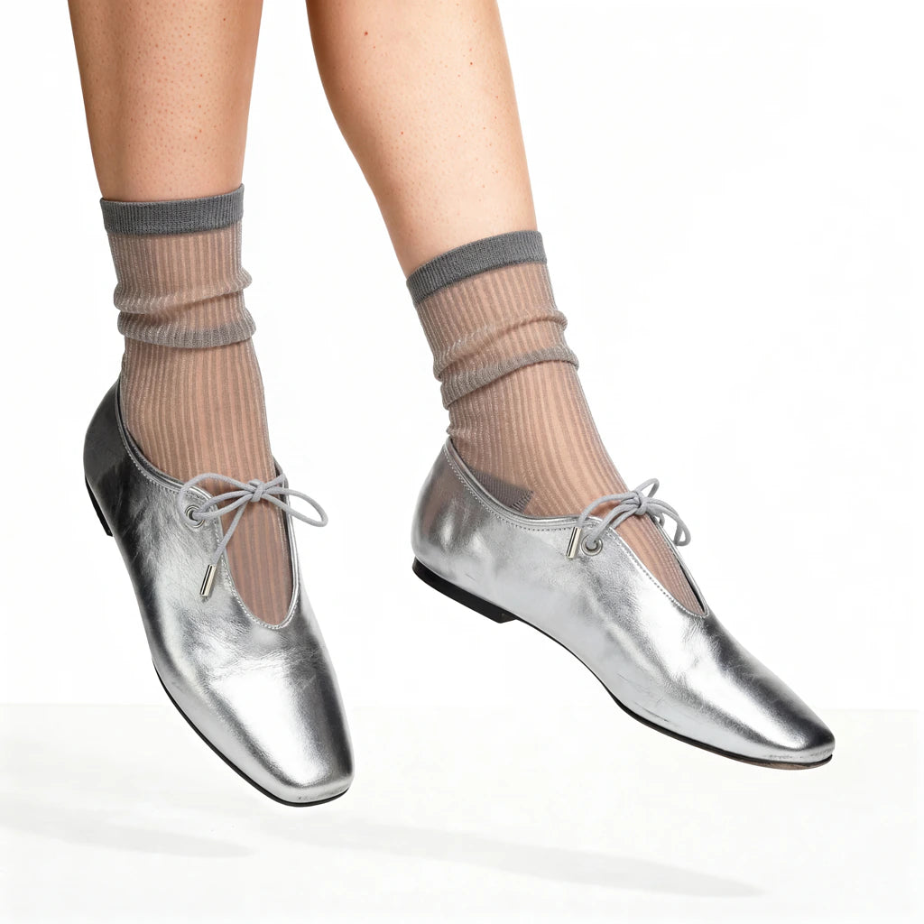 Silver shoes worn with grey socks on a white background