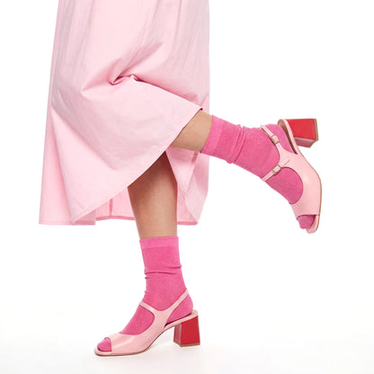 Pink high-heeled shoes and socks worn with a pink skirt on a white background