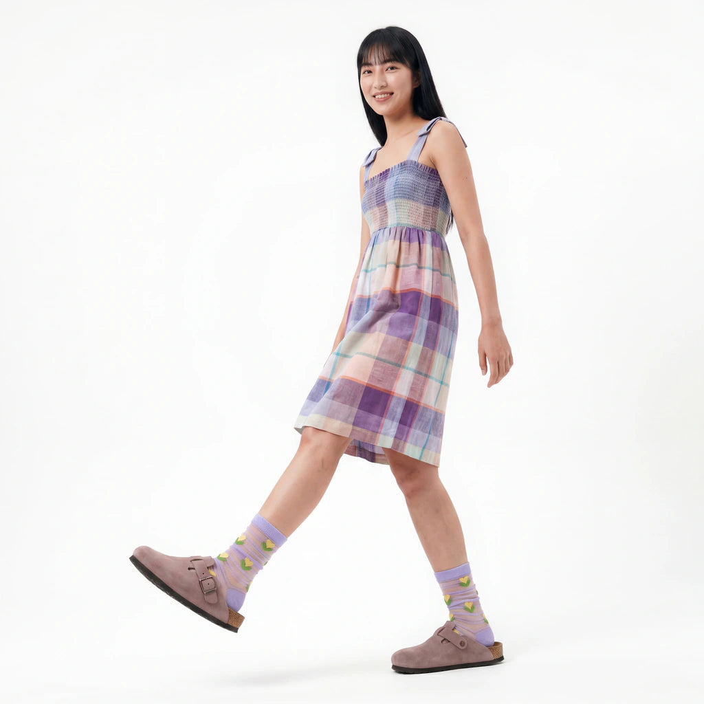 Woman wearing a plaid dress and colorful socks on a white background