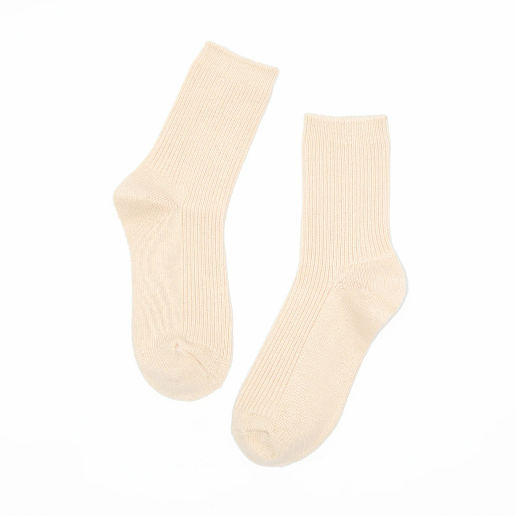 A pair of ribbed crew socks in a warm cream or off-white color, displayed against a solid white background.