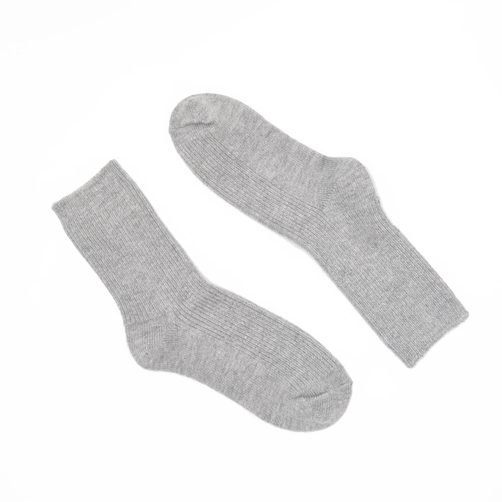 A pair of light gray ribbed crew socks laid flat on a solid white background.