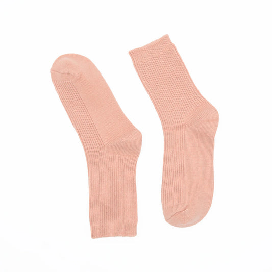 A pair of ribbed crew socks in a soft peach-pink color, displayed flat against a solid white background.