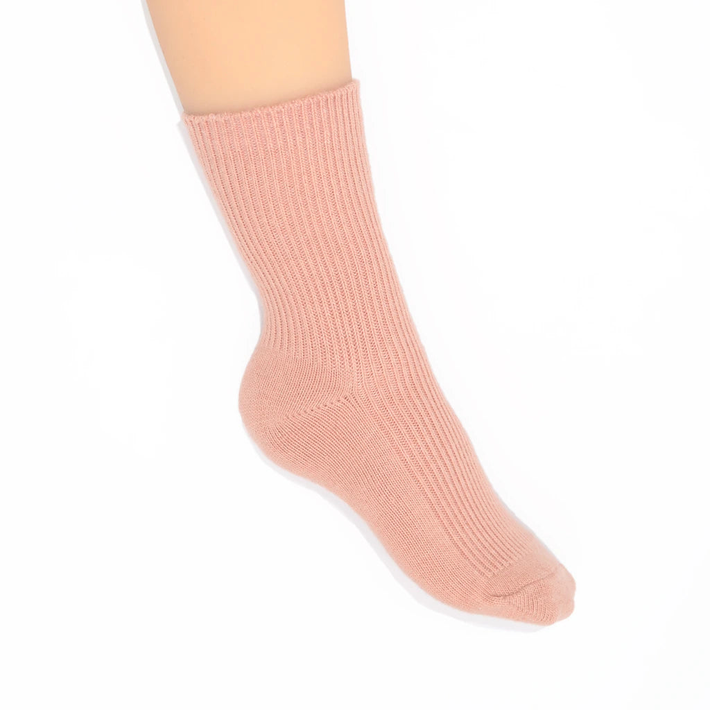 A single ribbed ankle sock in a soft dusty pink color, shown on a leg against a plain white background.