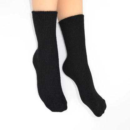 A pair of black ribbed crew socks on feet, shown against a plain white background.