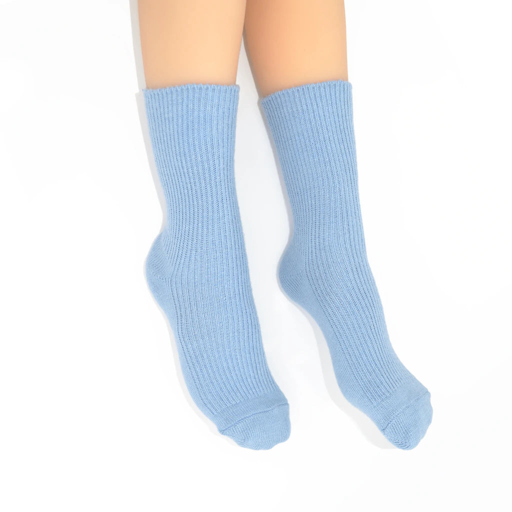 Light blue ribbed crew socks worn on  legs against a plain white background.