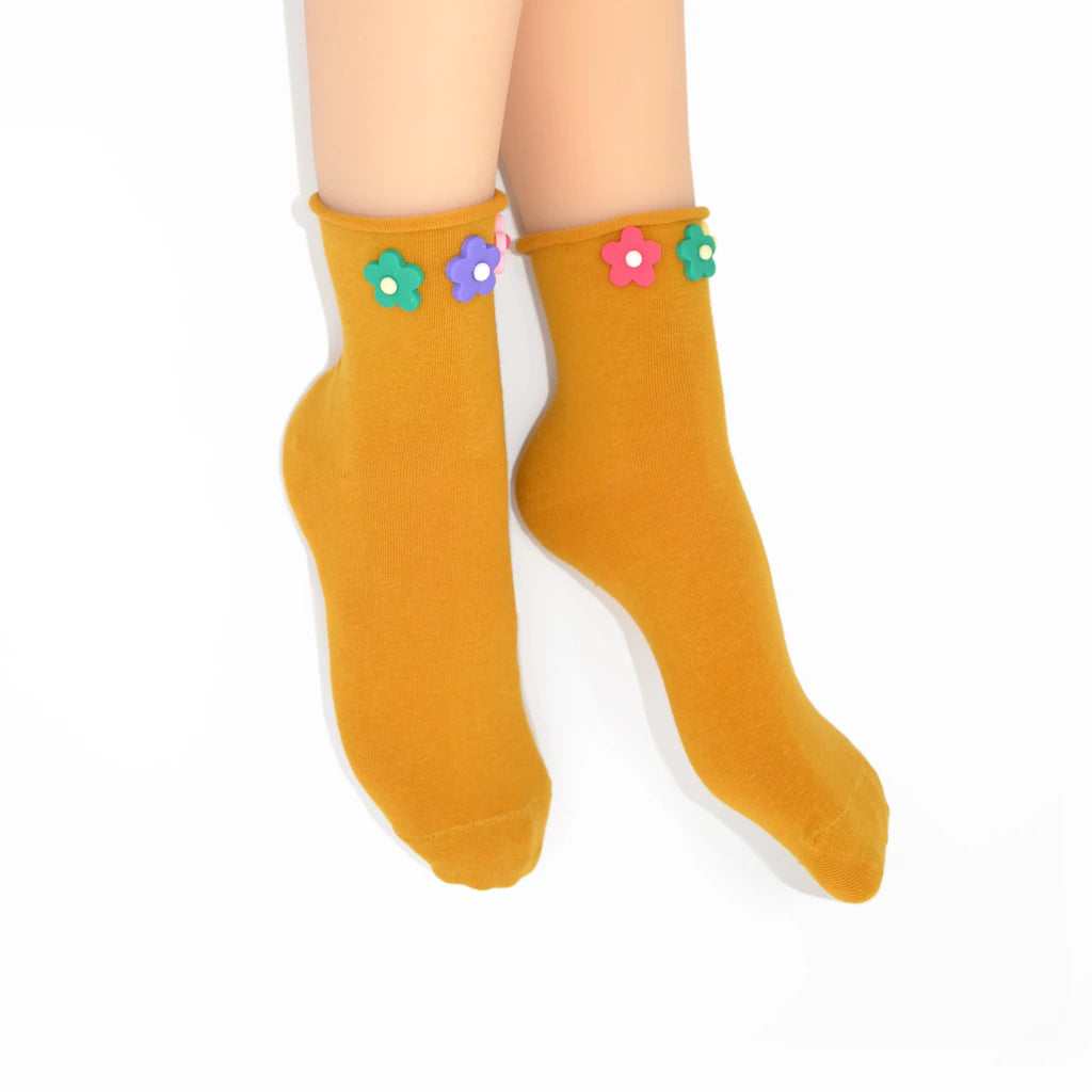 Mustard yellow socks with colorful flower decorations on a white background